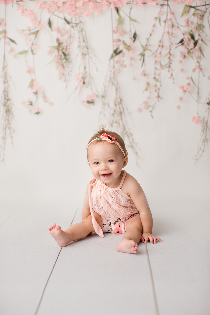 A happy baby sits in a studio in a pink outfit and matching headband after visiting Calvary Day Care Springfield, IL