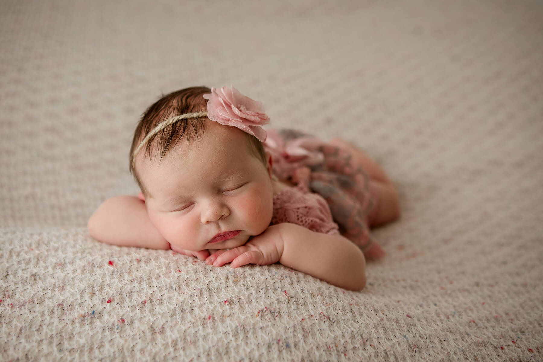 A baby girl sleeps on her tummy in a pink floral headband after visiting baby stores in springfield il