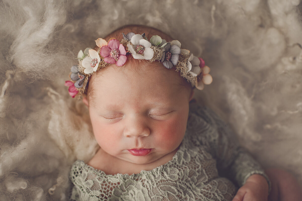 Closeup of a sleeping newborn in a lace dress and floral headband after meeting postpartum doulas in Springfield, IL