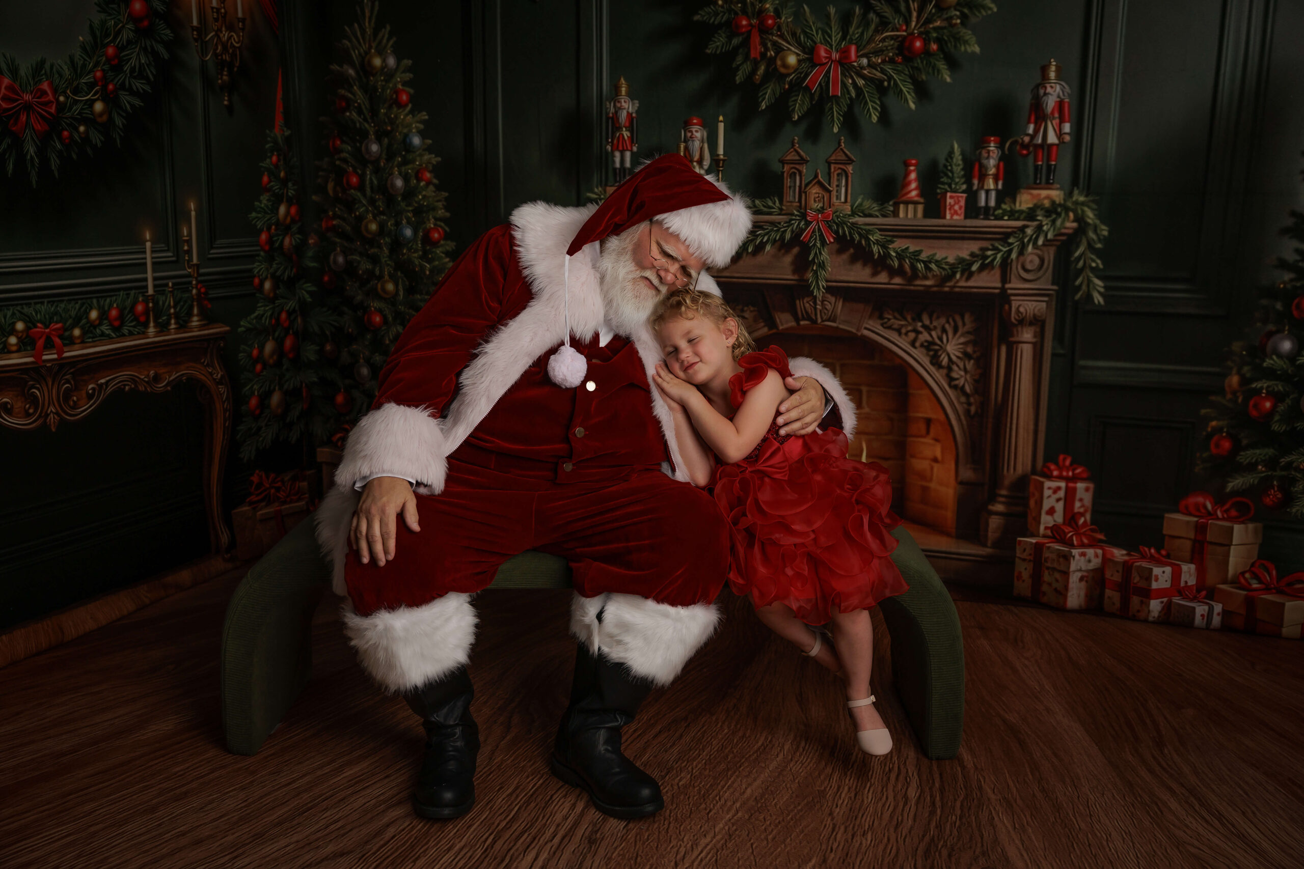 A toddler girl in a red dress cuddles on a Santa in Springfield, IL sitting on a bench