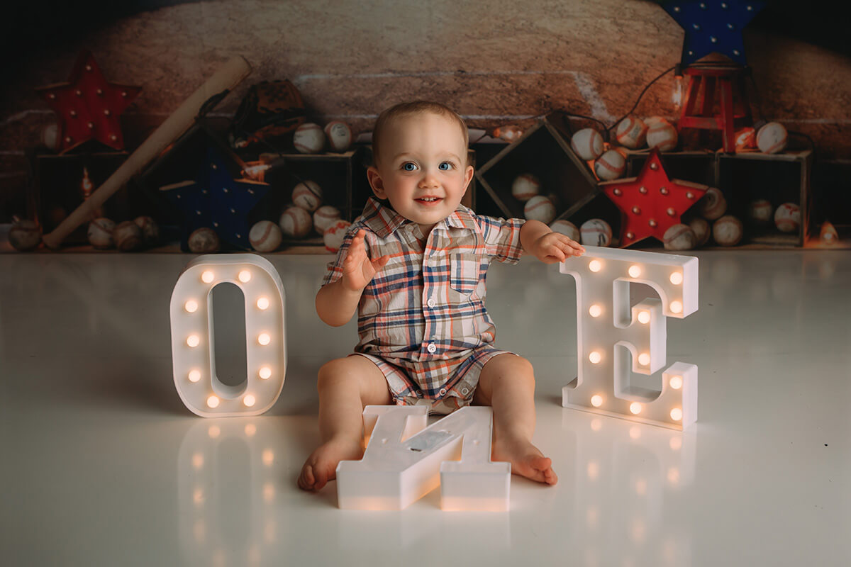 A happy baby in a plaid romper plays with the letters spelling one with little lights in a studio before some things to do in springfield il with toddlers