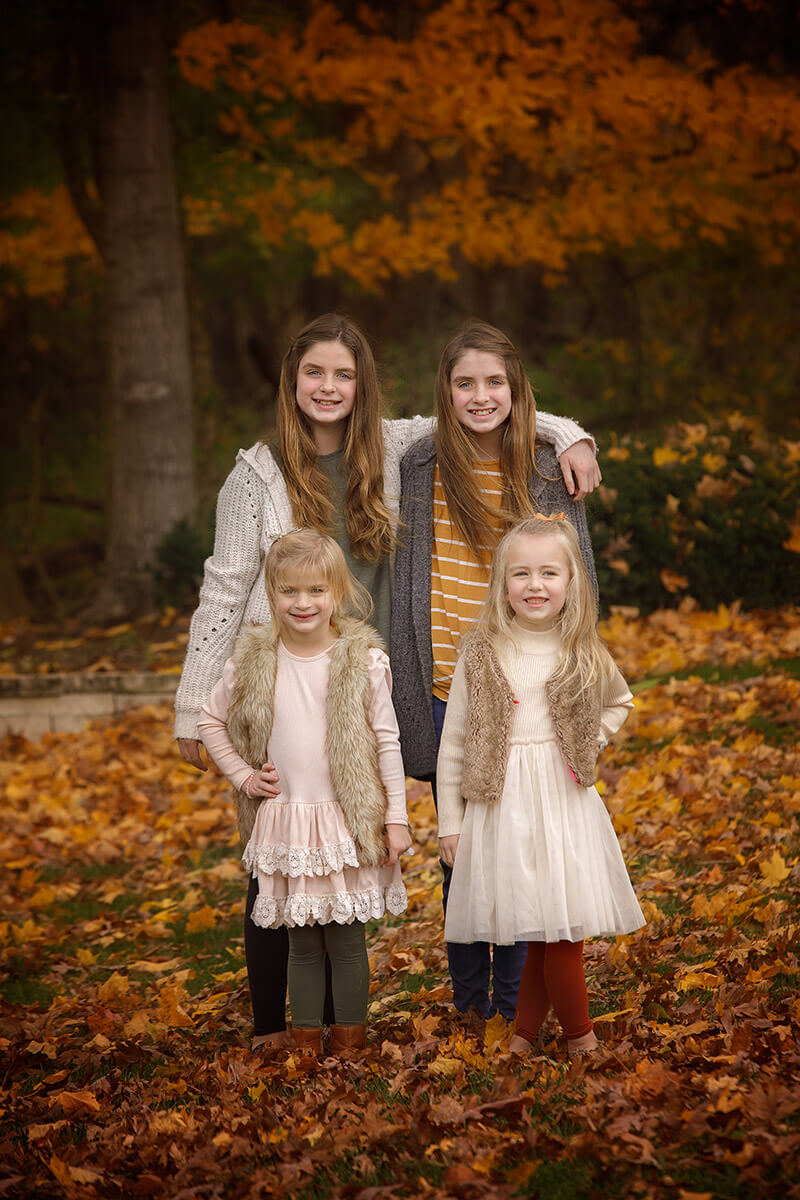 Happy cousins stand smiling in a park with hands on their hips during fall