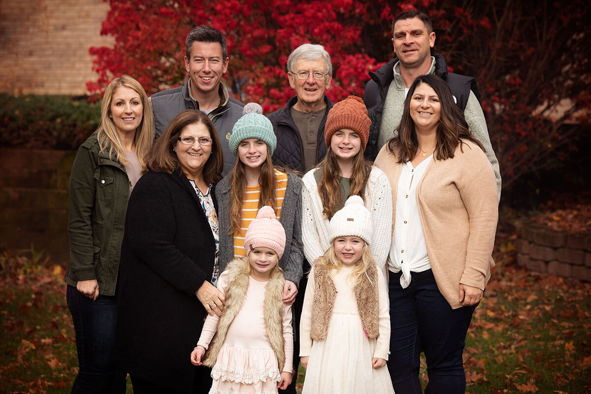 An extended family stands in a park in fall in sweaters and jackets in one of the parks in Springfield, IL