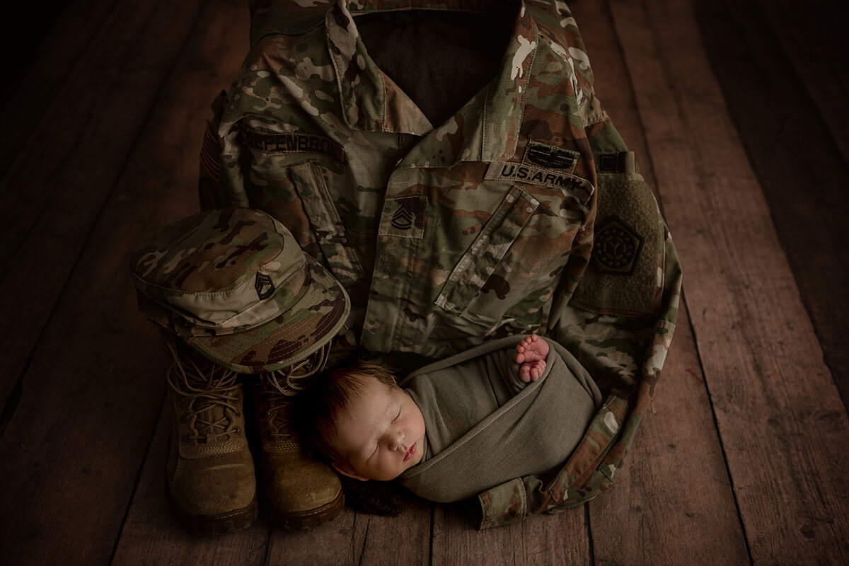 A sleeping newborn baby in a forest green swaddle on an army BDU after getting a 3d ultrasound in Springfield, IL