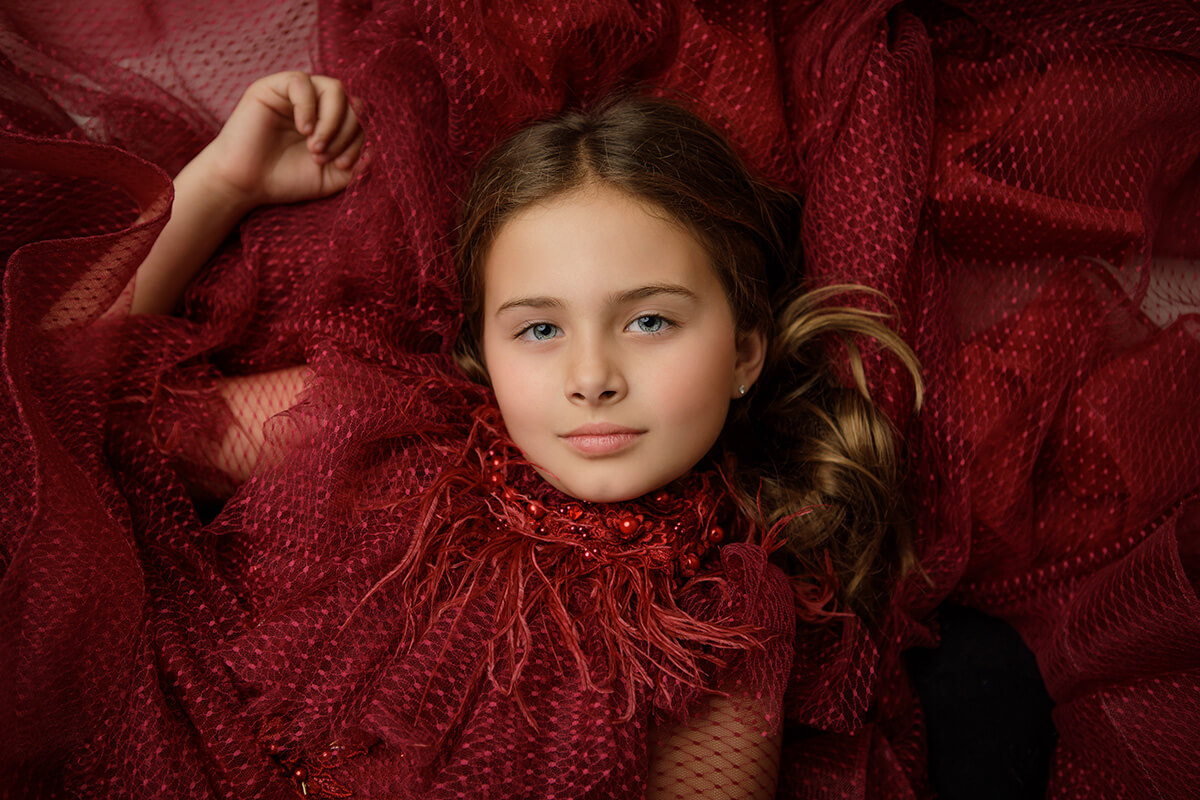 A closeup of a young girl as she lays in a her red gown before visiting an apple orchard in Springfield, IL