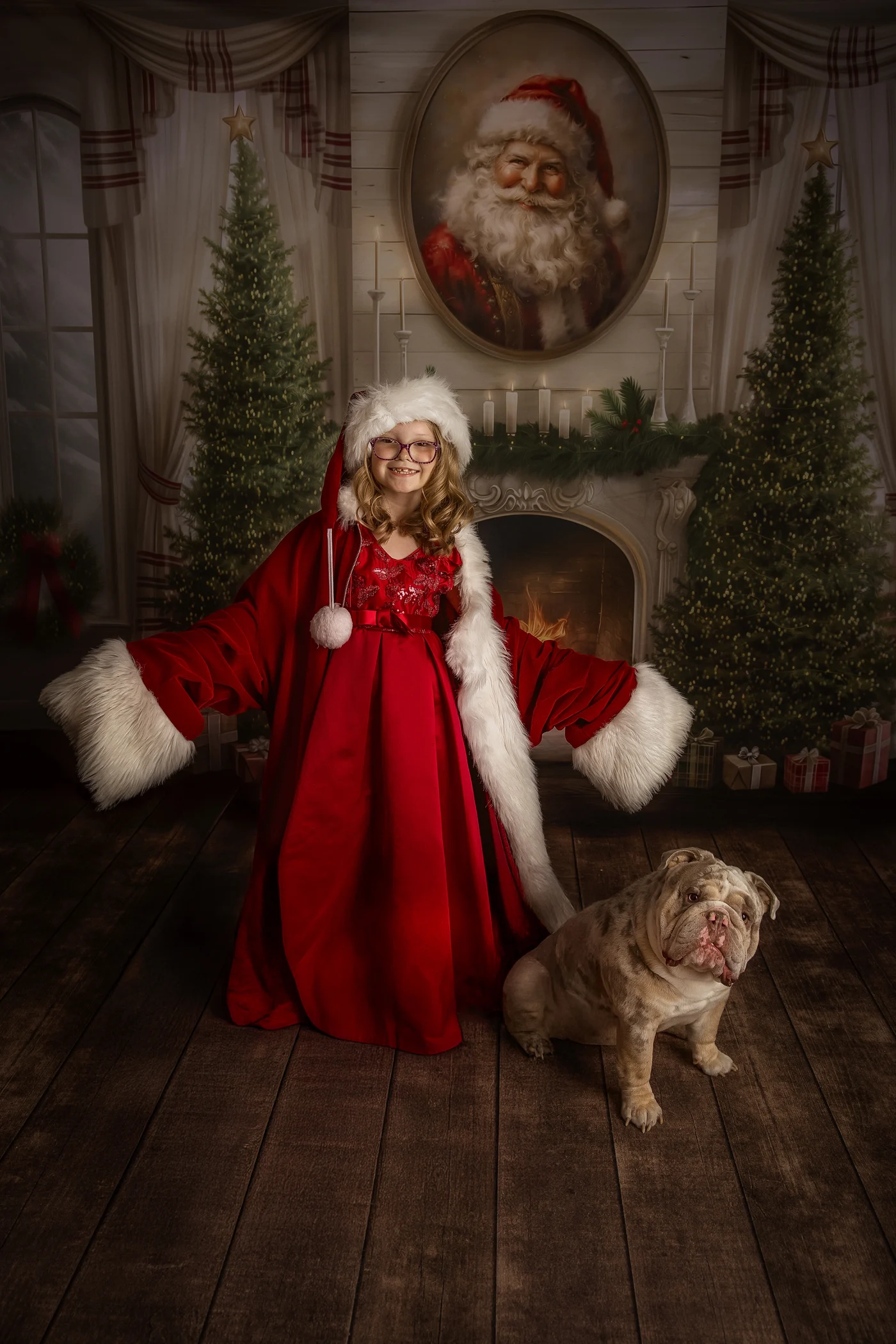 A young in a red dress opens her arms with a santa jacket on with her bulldog in front of christmas trees in springfield il