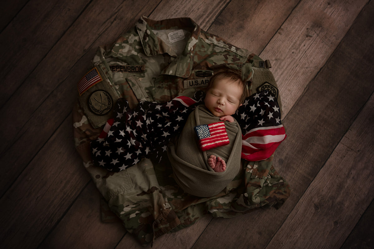 A sleeping newborn in a forest green swaddle on an army bdu after a 3d ultrasound in bloomington il