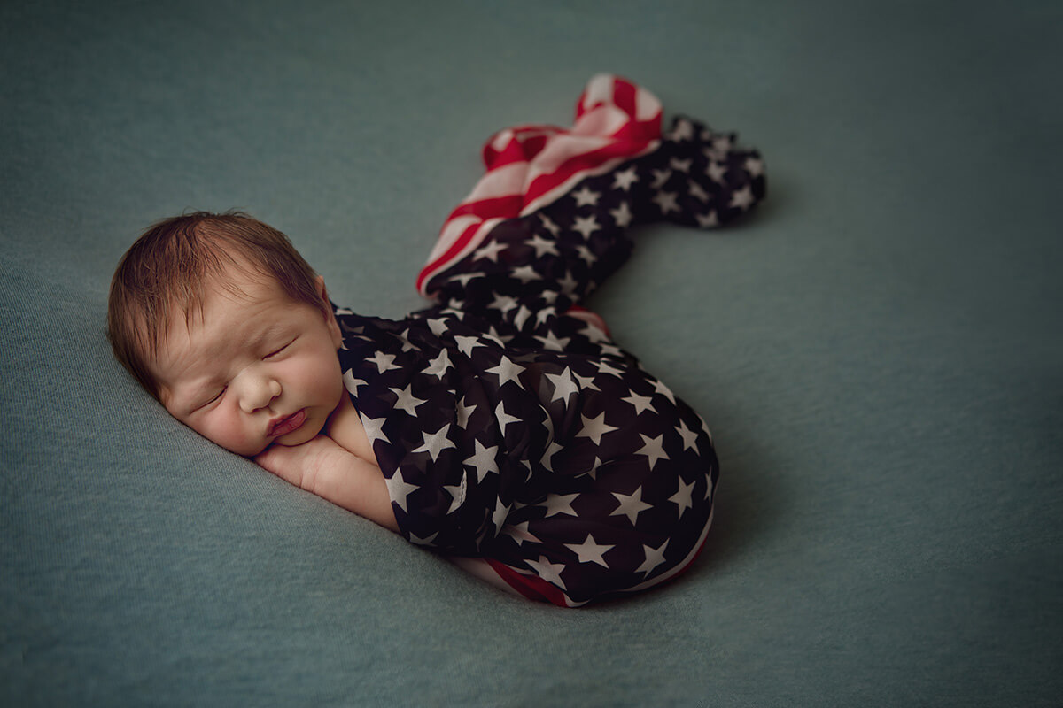 A newborn sleeping while wrapped in an american flag swaddle after a 3d ultrasound in bloomington il