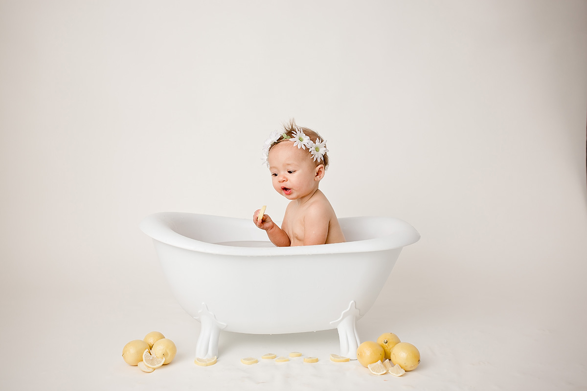A happy baby plays in. tiny bathtub with lemons on the ground after visiting pediatricians in bloomington il
