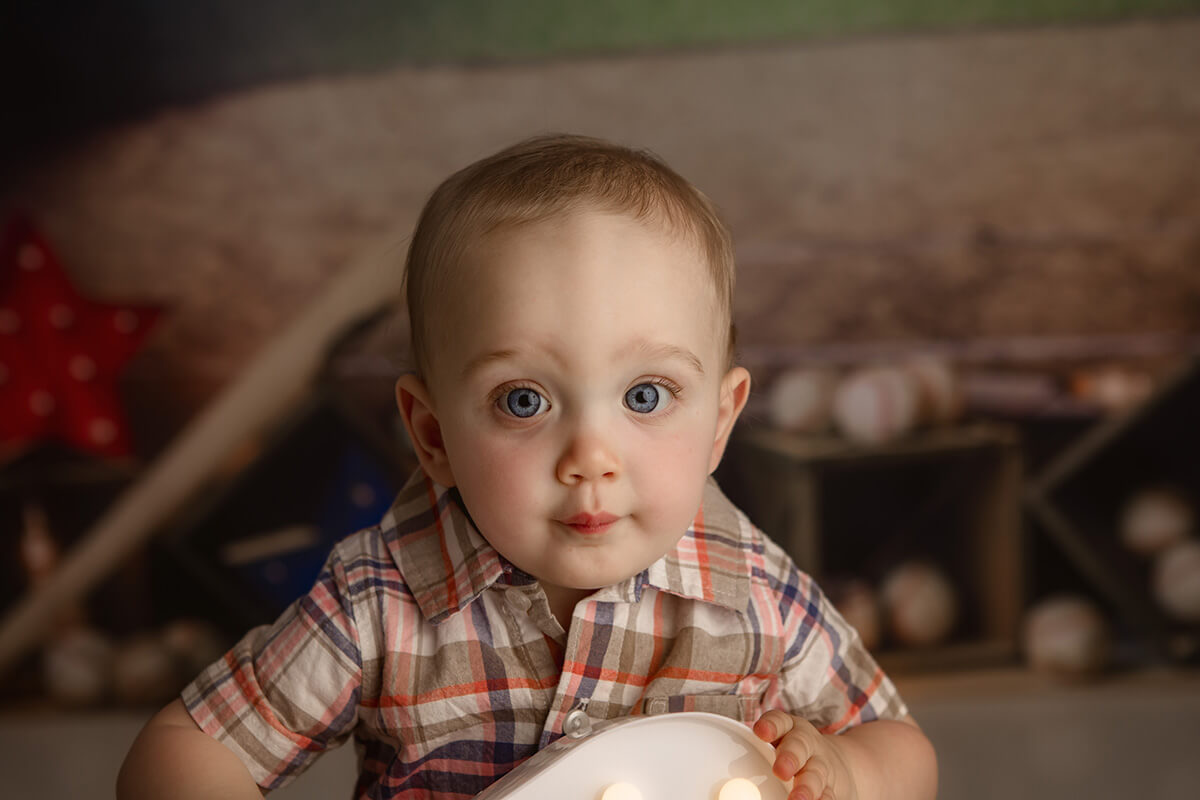 A toddler boy with big blue eyes in a plaid shirt in a studio after finding playgrounds in Bloomington, IL