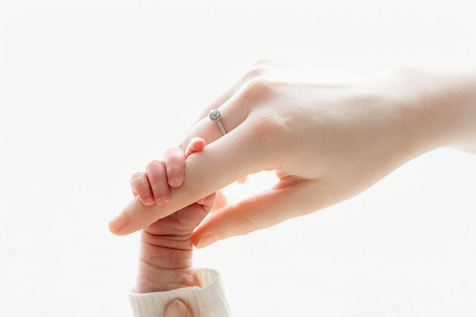 Details of a mother's finger being held by a newborn hand
