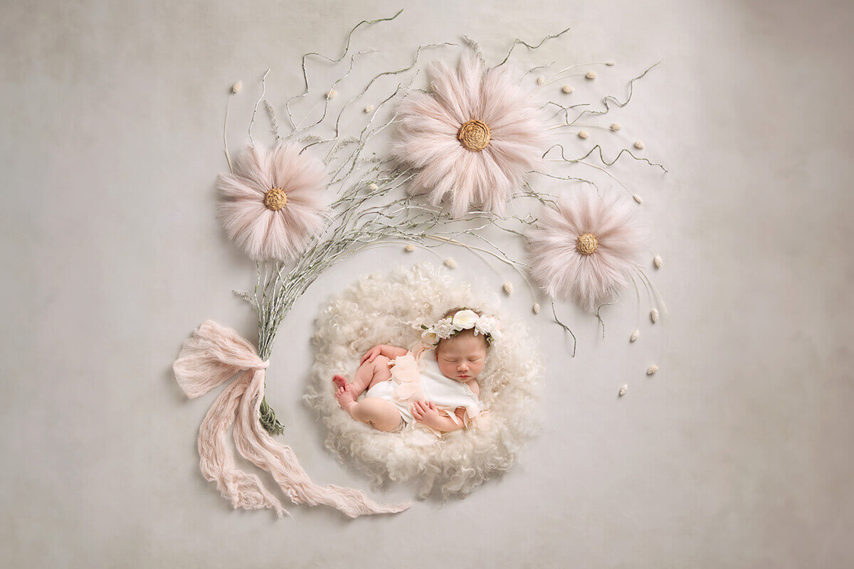 A newborn girl sleeps draped in white flowers on a fur bed after using baby shower venues in champaign il