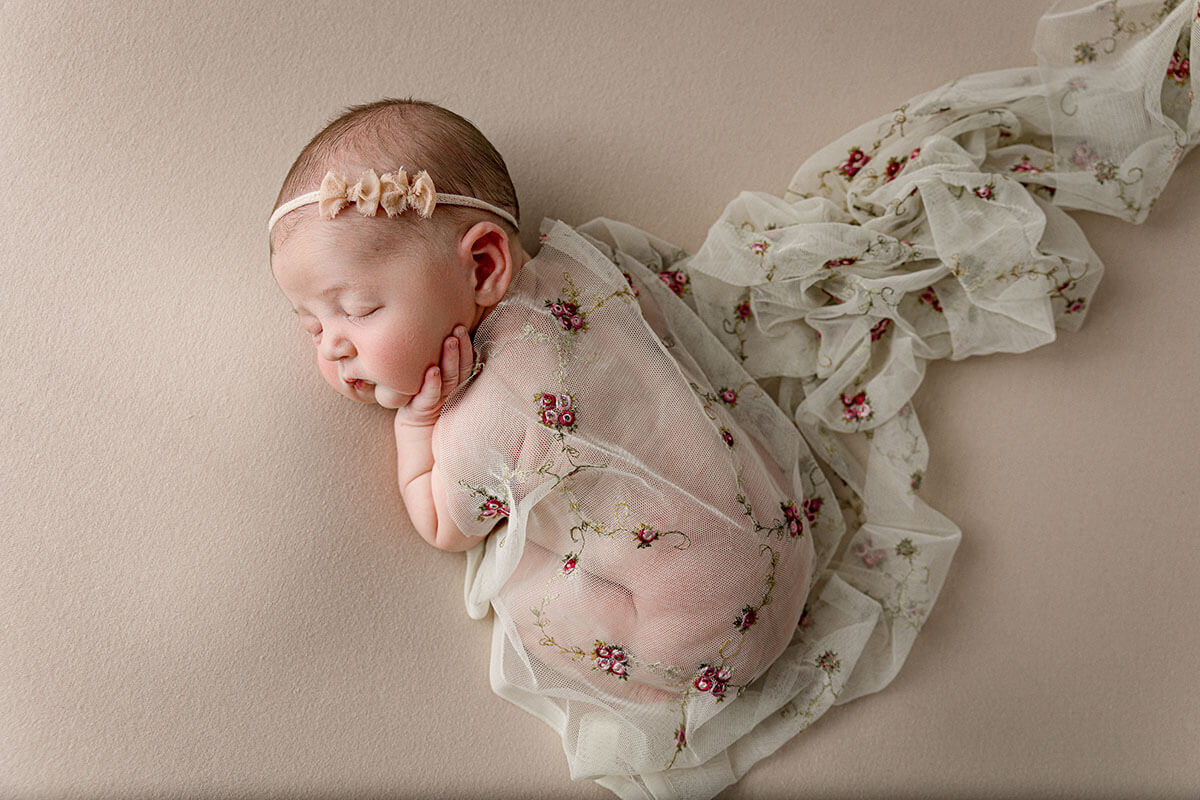 A newborn baby sleeps in a lace embroidered blanket in a studio after mom enjoyed prenatal yoga in champaign il