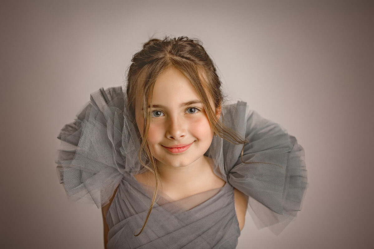 A young girl in a grey tulle dress smiles in a studio after loving private schools in champaign il